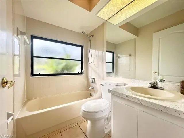 Full bathroom featuring tile patterned floors, toilet, vanity, and tiled shower / bath