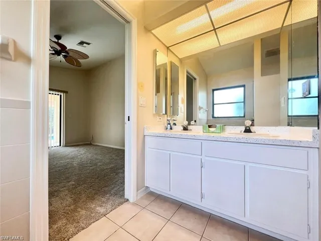 Bathroom with tile patterned floors, ceiling fan, and dual bowl vanity