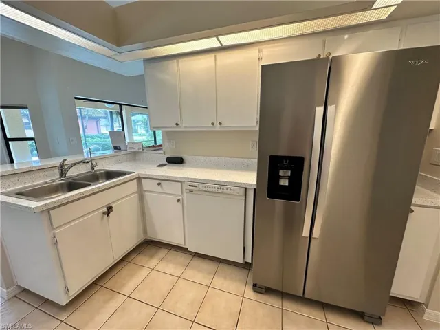 Kitchen with light tile patterned flooring, stainless steel appliances, and white cabinets
