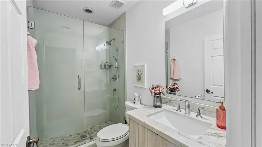 Bathroom with toilet, a shower with shower door, and vanity