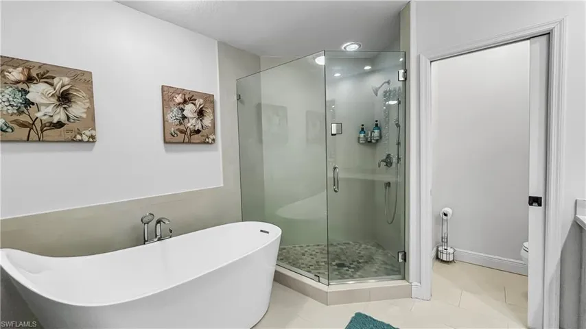 Bathroom featuring toilet, tile patterned flooring, and shower with separate bathtub