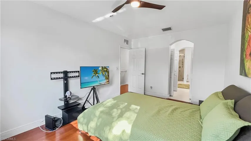 Bedroom featuring ceiling fan, ensuite bathroom, and wood-type flooring