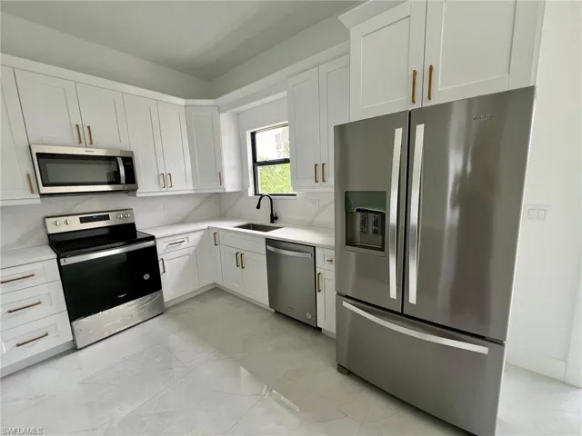Kitchen with sink, appliances with stainless steel finishes, and white cabinets