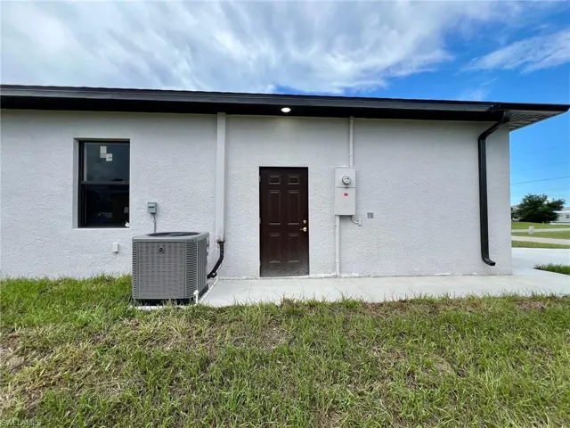 Rear view of property featuring central AC and a yard
