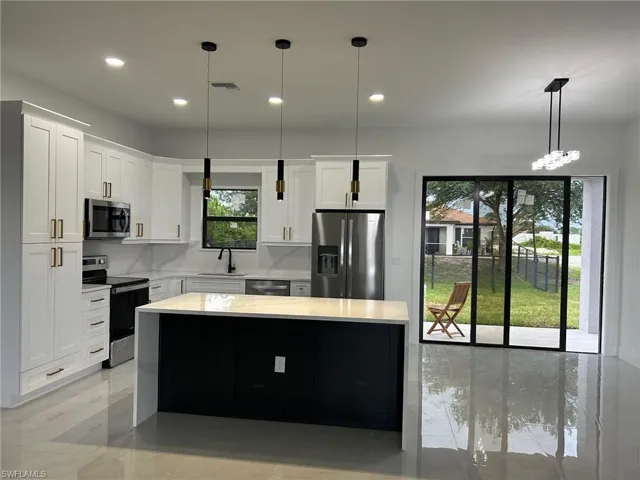 Kitchen featuring tasteful backsplash, decorative light fixtures, appliances with stainless steel finishes, and sink