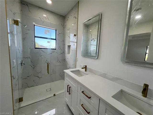 Bathroom with tile patterned flooring, double sink vanity, and an enclosed shower