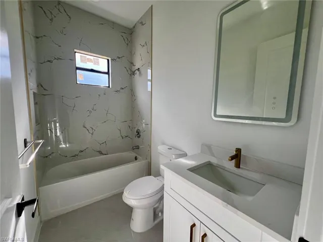 Full bathroom featuring tile patterned flooring, toilet, tiled shower / bath combo, and vanity