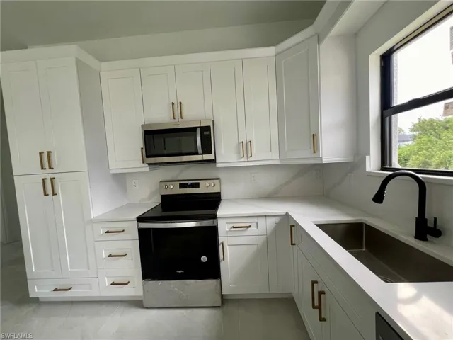 Kitchen featuring appliances with stainless steel finishes, white cabinetry, sink, and light tile patterned flooring