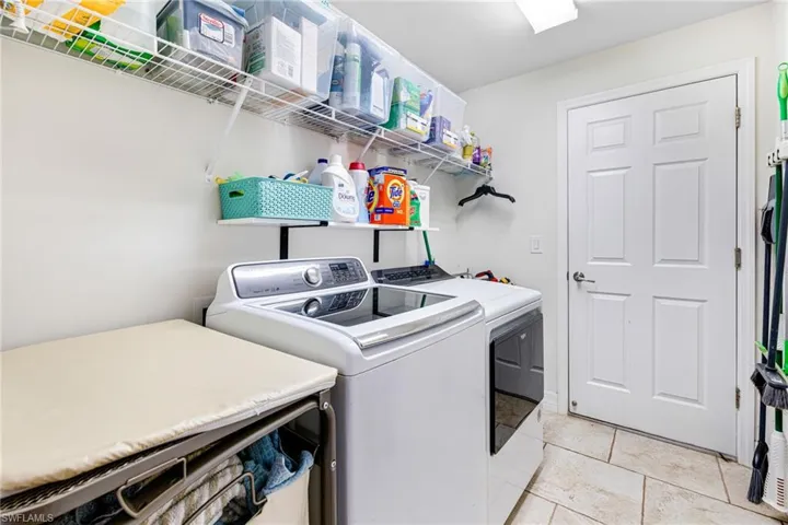 Washroom with washer and clothes dryer and light tile patterned flooring