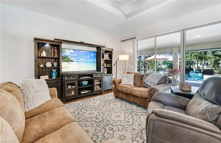 Living room featuring light wood-type flooring, a tray ceiling, and crown molding