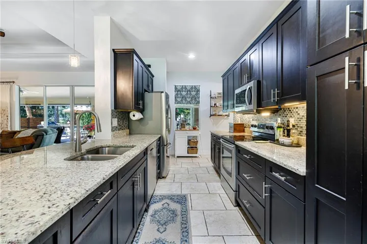 Kitchen featuring decorative light fixtures, sink, stainless steel appliances, and tasteful backsplash