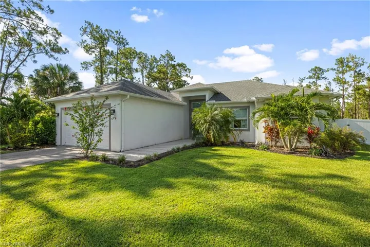 Ranch-style home with an attached garage, stucco siding, driveway, and a front yard