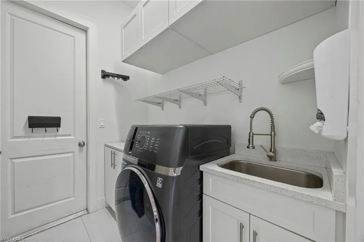 Laundry room featuring cabinet space and light tile patterned flooring