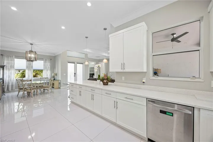 Kitchen featuring ornamental molding, white cabinetry, stainless steel dishwasher, decorative light fixtures, and light tile patterned floors