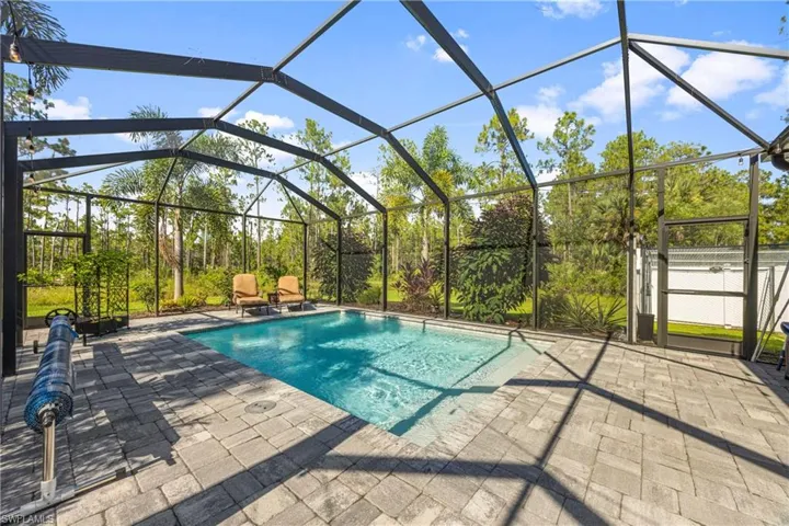 Outdoor pool with a sunroom, glass enclosure, a patio area, and a gate
