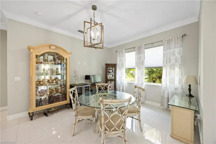 Dining area with crown molding, a chandelier, and light tile patterned flooring