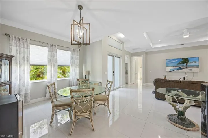 Dining room featuring french doors, ornamental molding, light tile patterned floors, a chandelier, and a tray ceiling
