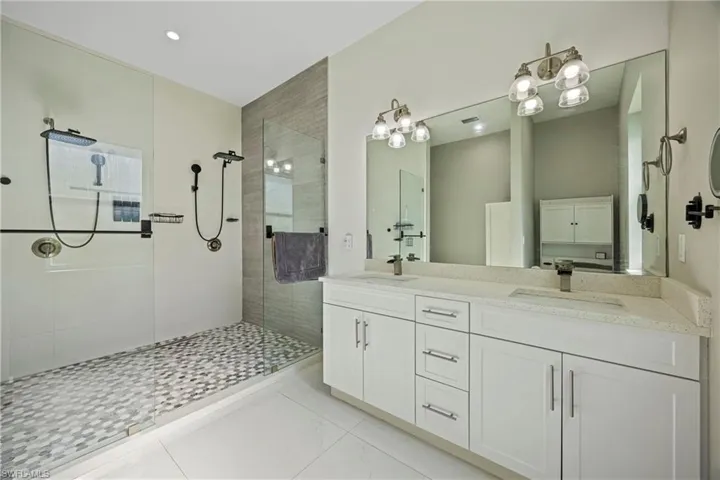 Full bathroom featuring double vanity, a walk in shower, and light tile patterned floors