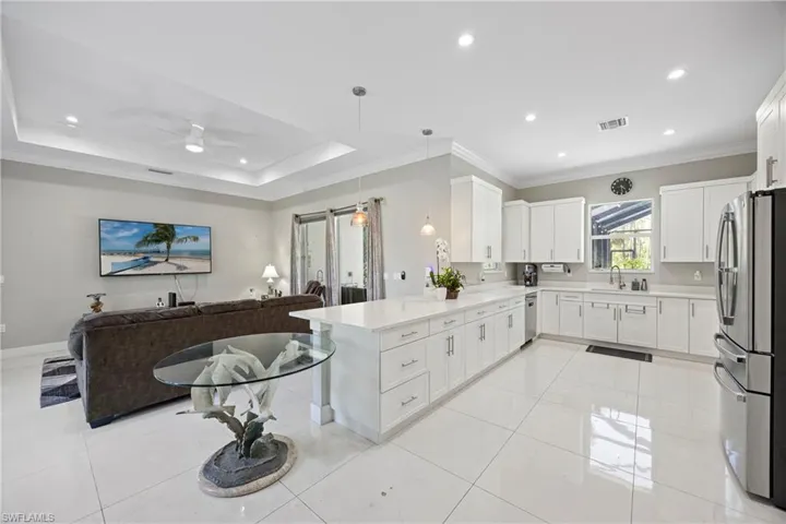 Kitchen with white cabinetry, open floor plan, stainless steel appliances, ornamental molding, and recessed lighting