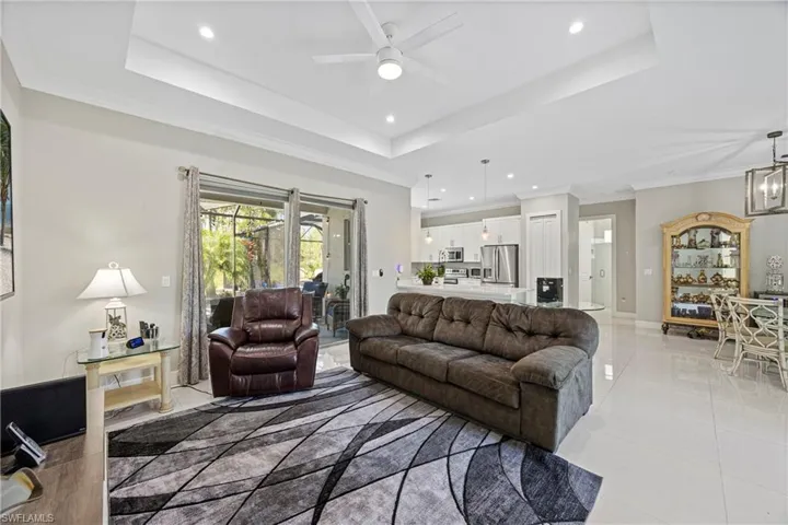 Living area featuring a tray ceiling, crown molding, recessed lighting, a chandelier, and light tile patterned floors