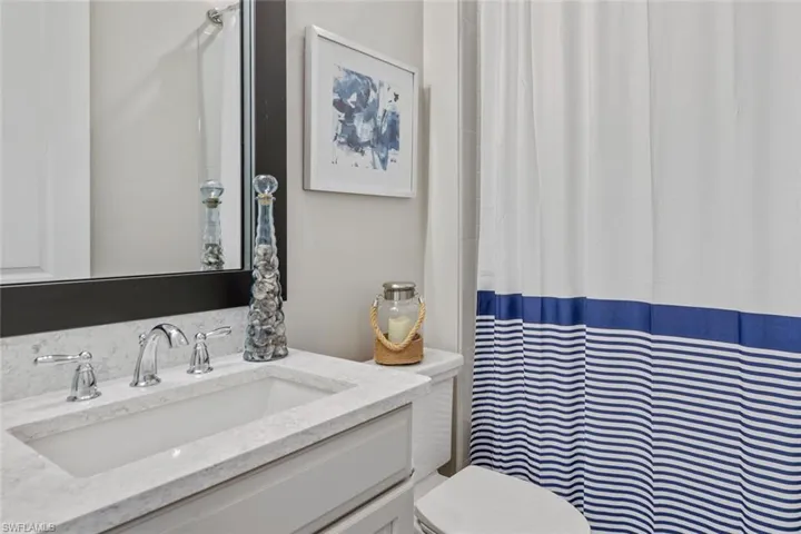 Step into the luxurious frameless glass walk-in shower, finished with oversized tile and a sleek window for natural light. The layout provides direct access to both the bedroom and the walk-in closet for effortless flow.