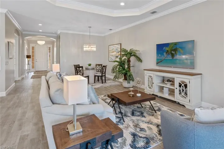 Expansive open-concept great room seamlessly connects to the outdoors with two sets of sliding glass doors leading to the extended lanai. Enjoy effortless indoor-outdoor living with panoramic views of the pool, lake, and lush surroundings, all framed by elegant wood-look tile flooring and stylish finishes.