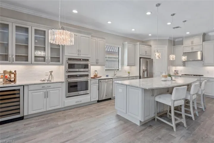 The designer kitchen with large quartz island and GE Café appliances overlooks the Great Room with sliding doors leading to an upgraded extended spacious lanai, perfect for outdoor living!