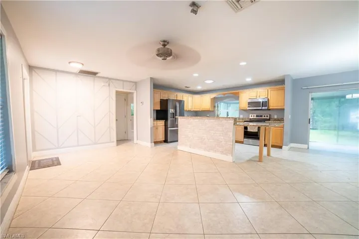 Kitchen featuring stainless steel appliances, a kitchen island, light tile patterned floors, and ceiling fan