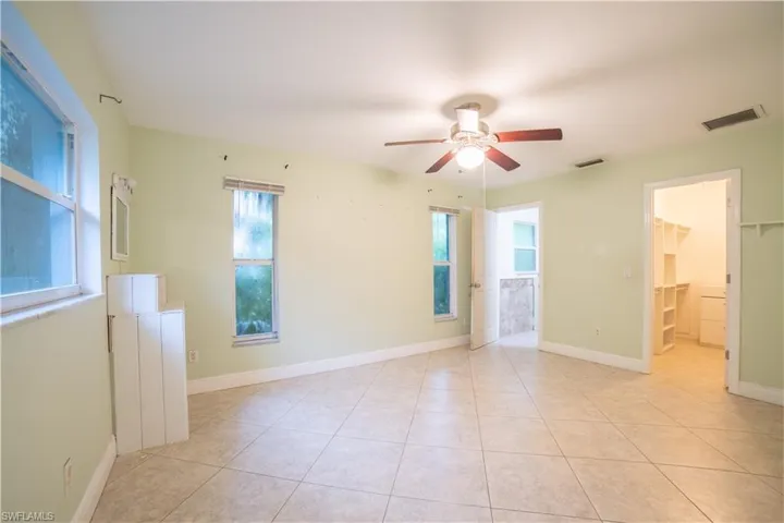 Spare room featuring ceiling fan, light tile patterned floors, and a wealth of natural light