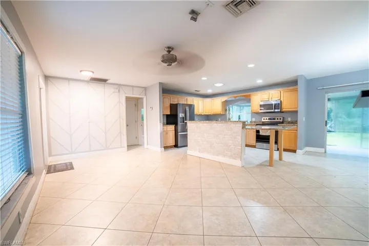 Kitchen with stainless steel appliances, light tile patterned floors, a center island, and ceiling fan