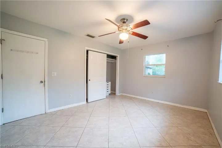 Unfurnished bedroom featuring ceiling fan, light tile patterned flooring, and a closet