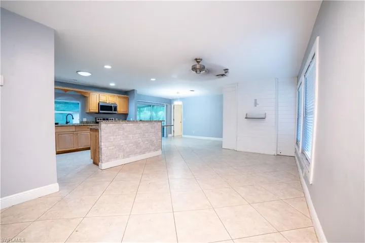 Kitchen featuring light tile patterned flooring, light stone countertops, ceiling fan, and sink