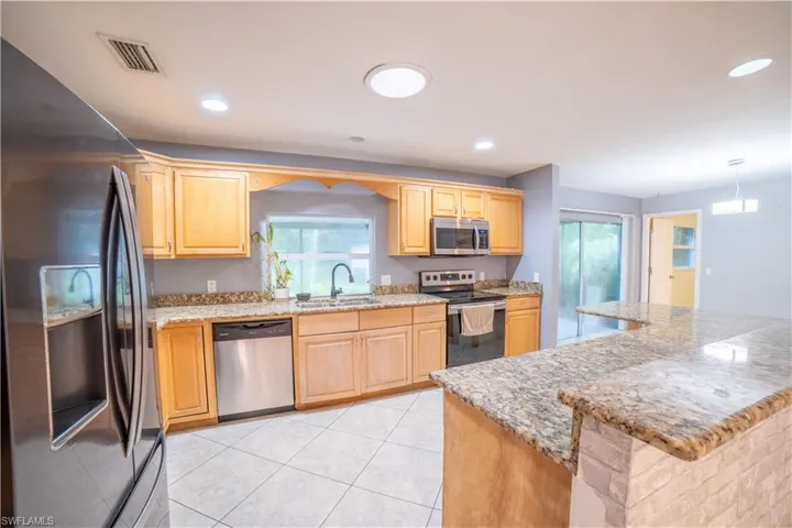 Kitchen featuring decorative light fixtures, appliances with stainless steel finishes, sink, and light brown cabinets