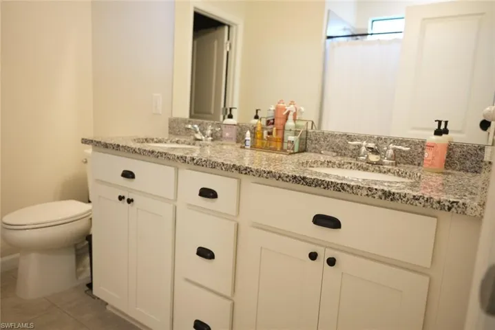 Bathroom with tile patterned flooring, vanity, toilet, and walk in shower
