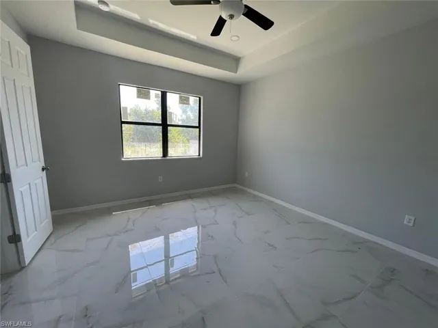 Empty room featuring a tray ceiling and tile floors