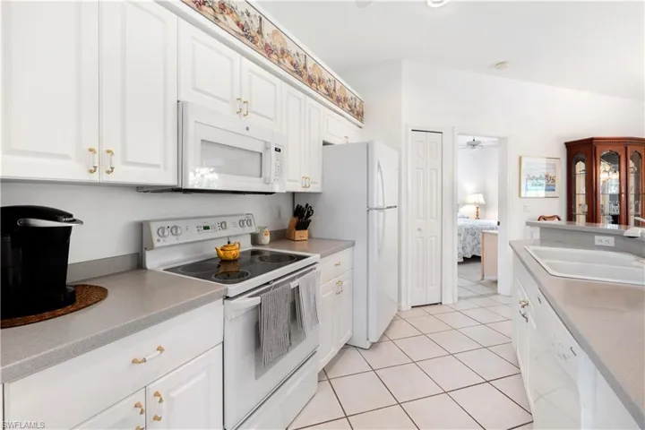 Kitchen featuring white cabinets, white appliances, and sink