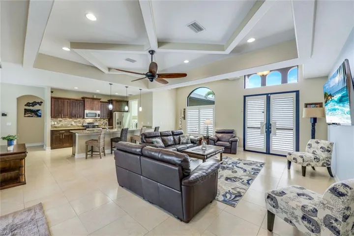 Tiled living room featuring ceiling fan, french doors, and beam ceiling