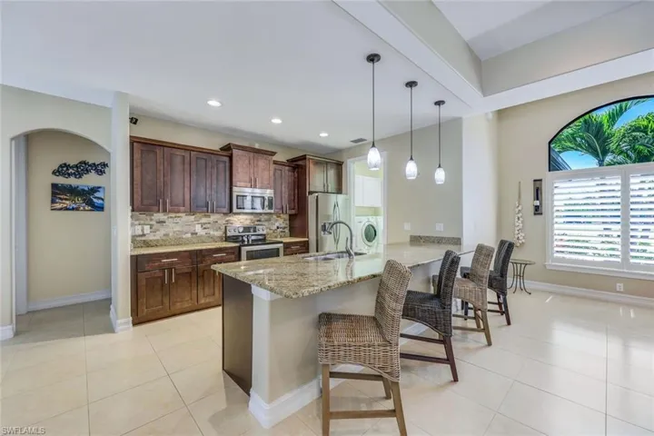 Kitchen with light tile flooring, a kitchen breakfast bar, tasteful backsplash, appliances with stainless steel finishes, and sink