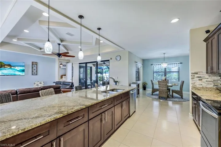 Kitchen with decorative light fixtures, sink, coffered ceiling, and ceiling fan with notable chandelier