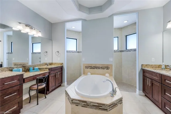 Bathroom featuring tiled bath, vanity, tile floors, and radiator