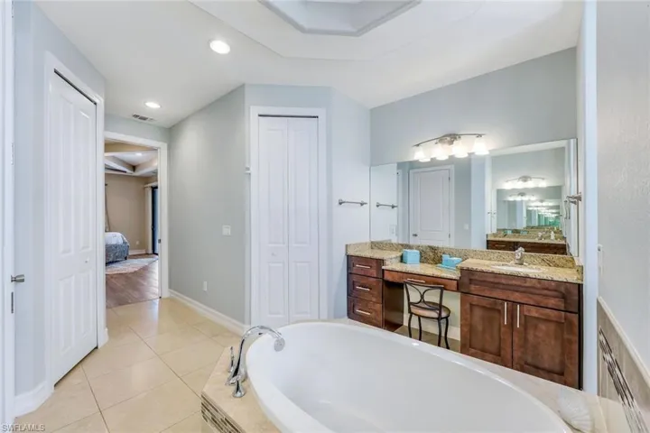 Bathroom with a raised ceiling, wood-type flooring, a bathing tub, and vanity
