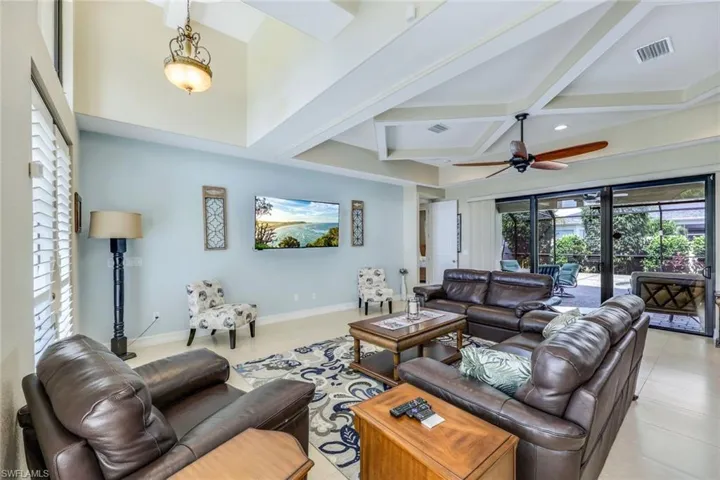 Tiled living room featuring beamed ceiling, coffered ceiling, and ceiling fan