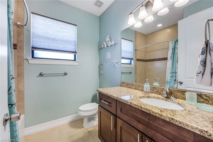 Bathroom with a wealth of natural light, tile flooring, vanity, and toilet