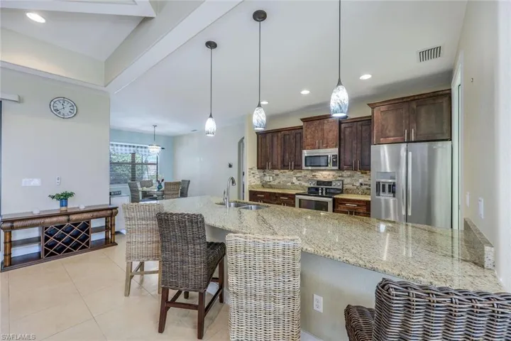 Kitchen with stainless steel appliances, backsplash, pendant lighting, sink, and a kitchen bar