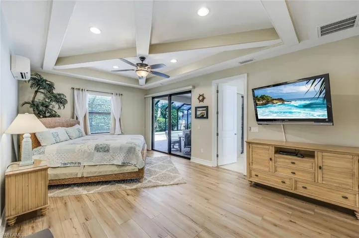 Bedroom featuring ceiling fan, beam ceiling, light wood-type flooring, an AC wall unit, and access to exterior