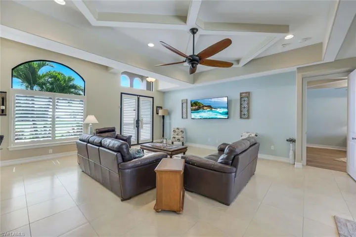Tiled living room featuring beam ceiling and ceiling fan