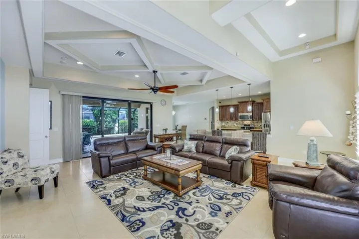 Tiled living room featuring beam ceiling, coffered ceiling, and ceiling fan