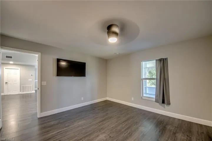 Master bedroom with ceiling fan, baseboards, and dark wood-type flooring