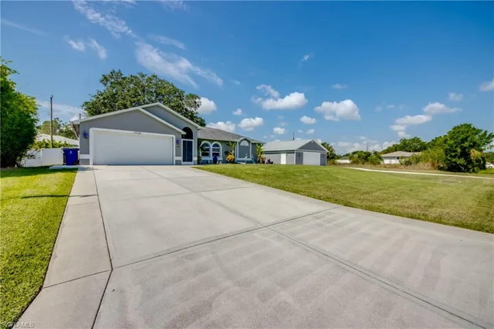 Single story home with a garage, a front lawn, driveway, and stucco siding