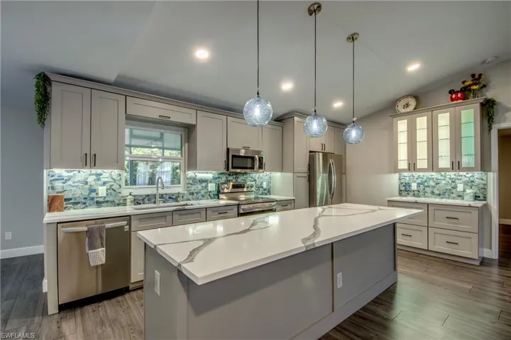 Kitchen with stainless steel appliances, a sink, tasteful backsplash, a center island, and vaulted ceiling